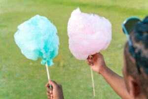 A happy black couple having colourful candy floss together in a park of a big city.
