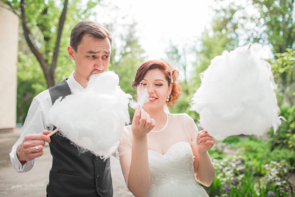 Wedding couple outside eating white cotton candy